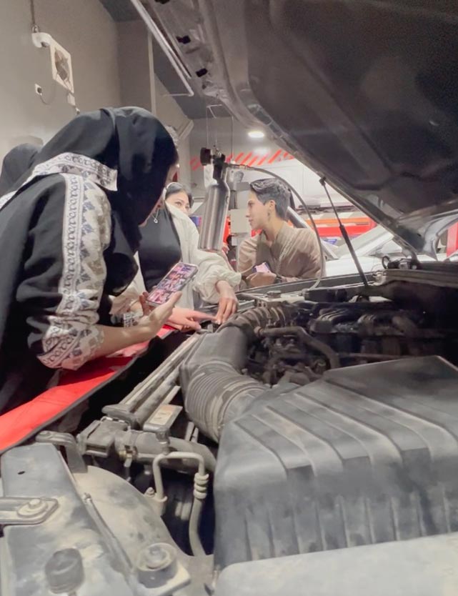 female customer learning about vehicle components in a free workshop