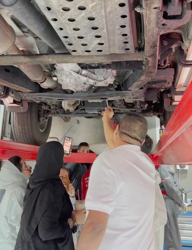 female customer learning about vehicle components in a free workshop